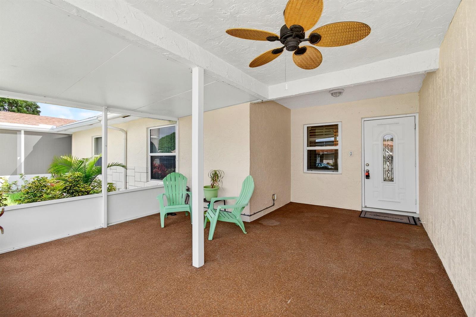 A covered patio with a ceiling fan, two light green chairs, and a white door — 6309 Dusenburg Road, Delray Beach FL 33484, DELRAY BEACH, FL