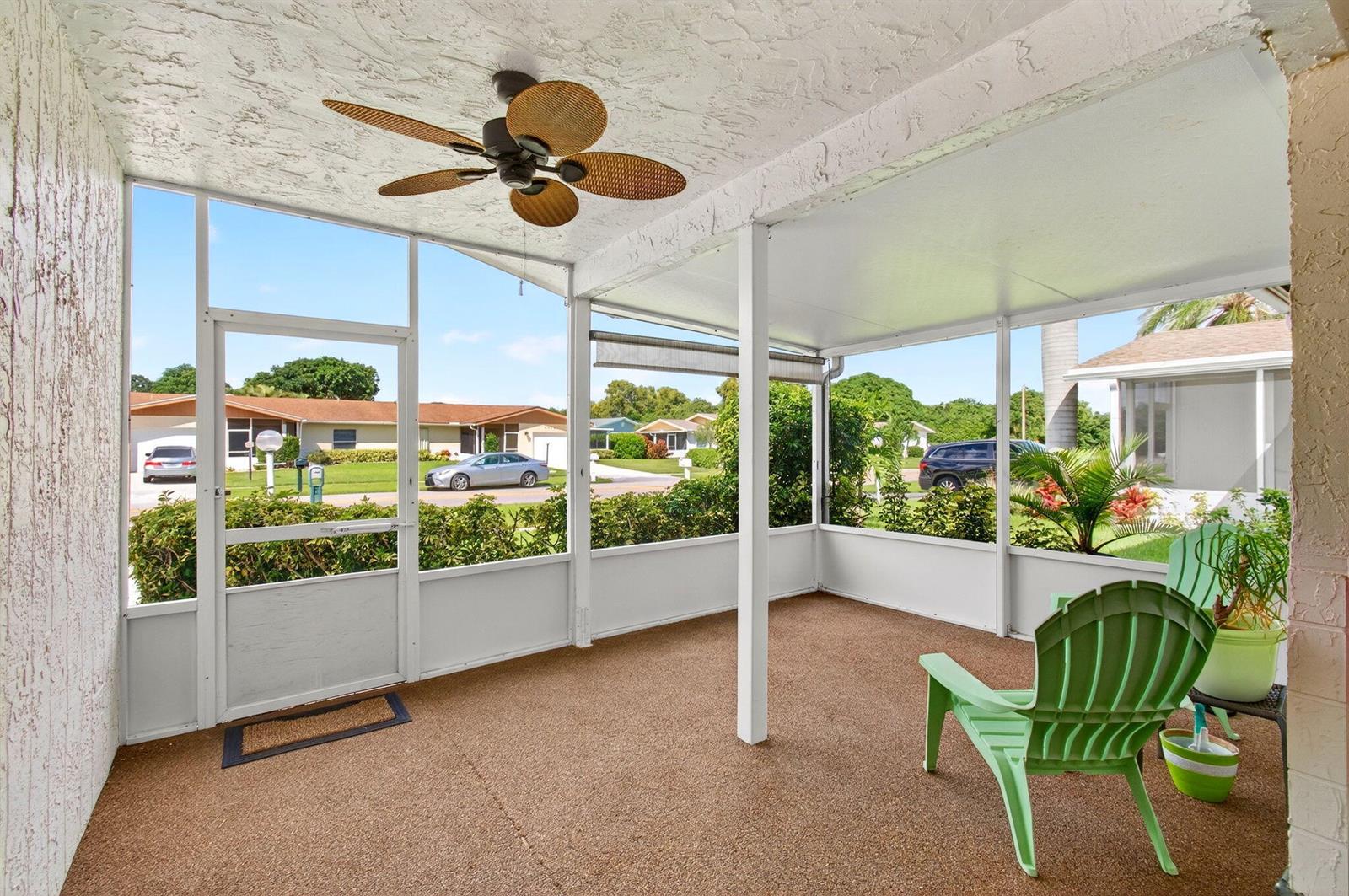 A screened-in porch features a textured ceiling, a ceiling fan, and green Adirondack chairs — 6309 Dusenburg Road, Delray Beach FL 33484, DELRAY BEACH, FL