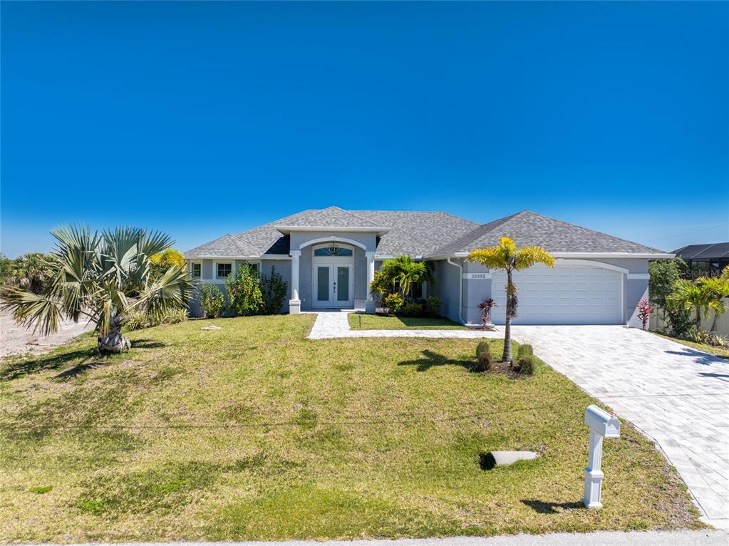 A single-story house with a gray exterior, a paved driveway, and a palm tree — 10392 RAINSVILLE STREET, PORT CHARLOTTE, FL