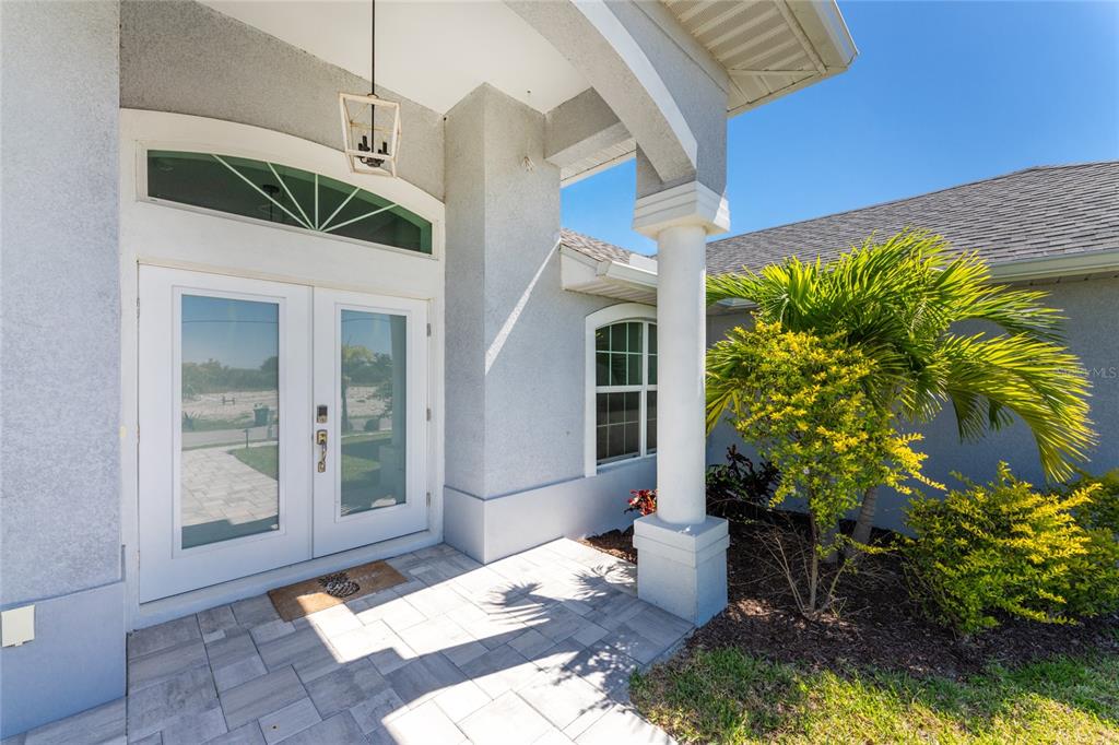A paved entryway features double glass doors, a white column, and a small palm tree — 10392 RAINSVILLE STREET, PORT CHARLOTTE, FL