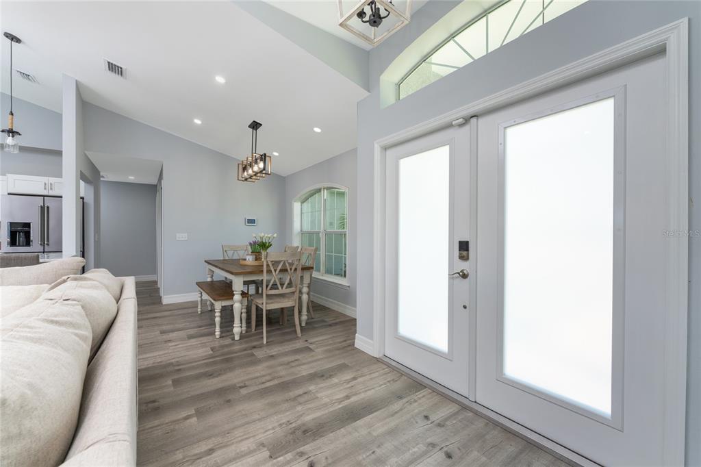 A dining area with a wooden table and chairs sits beside a white double-door entrance — 10392 RAINSVILLE STREET, PORT CHARLOTTE, FL