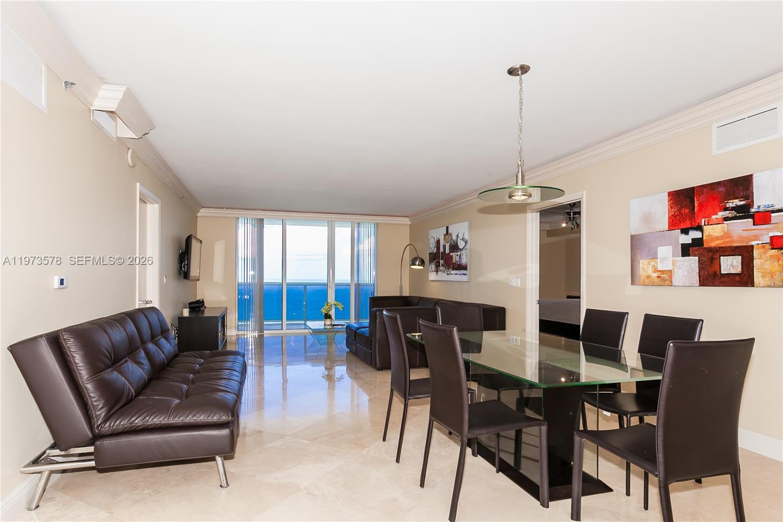 A living and dining area features dark leather furniture, a glass table, and ocean views — 1800 S OCEAN DR # 3803, Hallandale Beach FL 33009, HALLANDALE BEACH, FL