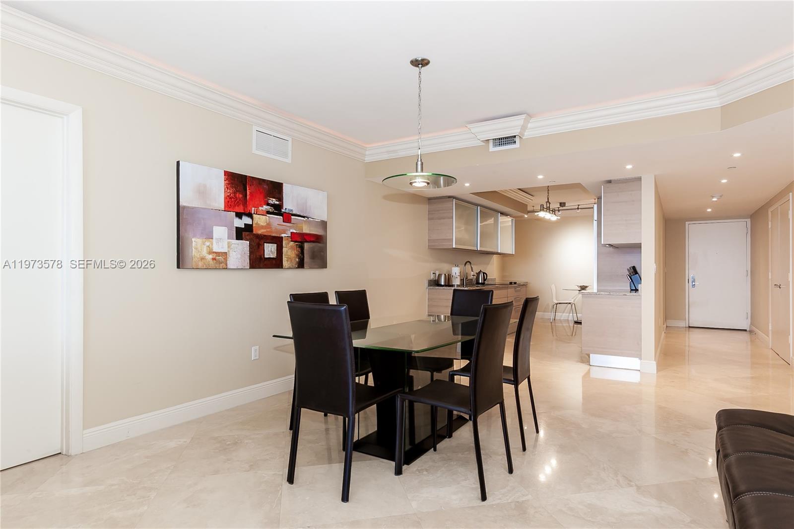 A dining area features a glass table, black chairs, and a modern light fixture — 1800 S OCEAN DR # 3803, Hallandale Beach FL 33009, HALLANDALE BEACH, FL