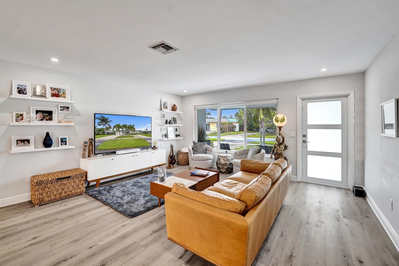 A living room features light wood floors, a tan leather sofa, and a television console — 381 SE 3rd Street, Pompano Beach FL 33060, POMPANO BEACH, FL