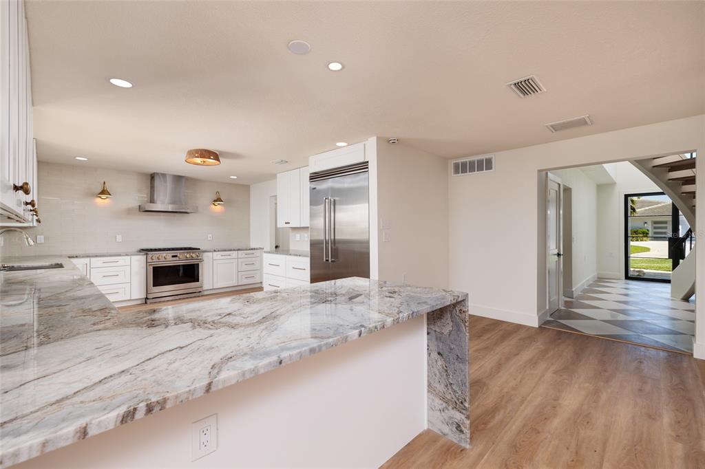 A kitchen with white cabinets, stone countertops, stainless steel appliances, and wood-look flooring — 2063 ILLINOIS AVENUE NE, ST PETERSBURG, FL