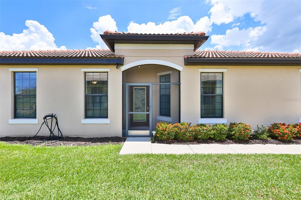 The exterior of a single-story house features a tiled roof, beige stucco, and a screened entryway — 5532 SUNSET FALLS DRIVE, APOLLO BEACH, FL
