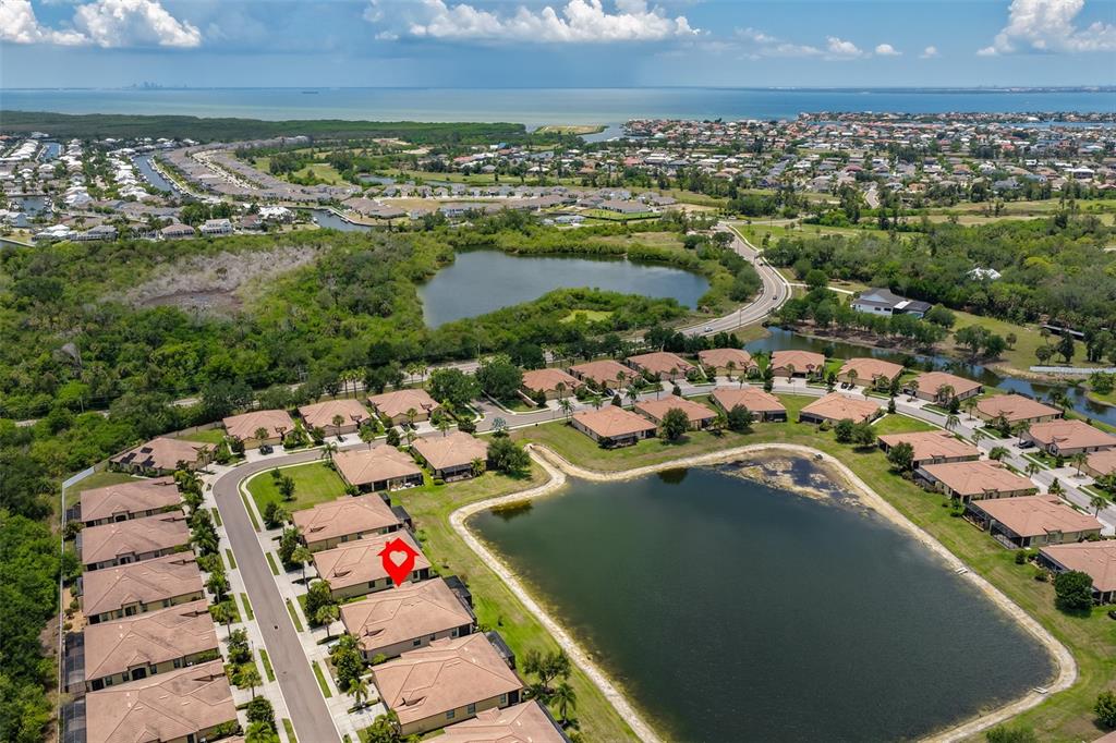 An aerial view shows a residential neighborhood with houses surrounding a large retention pond — 5532 SUNSET FALLS DRIVE, APOLLO BEACH, FL