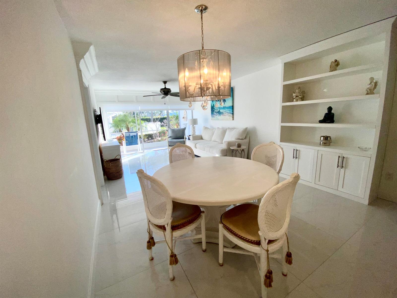 A dining area with a round table and cane chairs sits before a white living room — 331 Tequesta Drive # 118, Tequesta FL 33469, TEQUESTA, FL