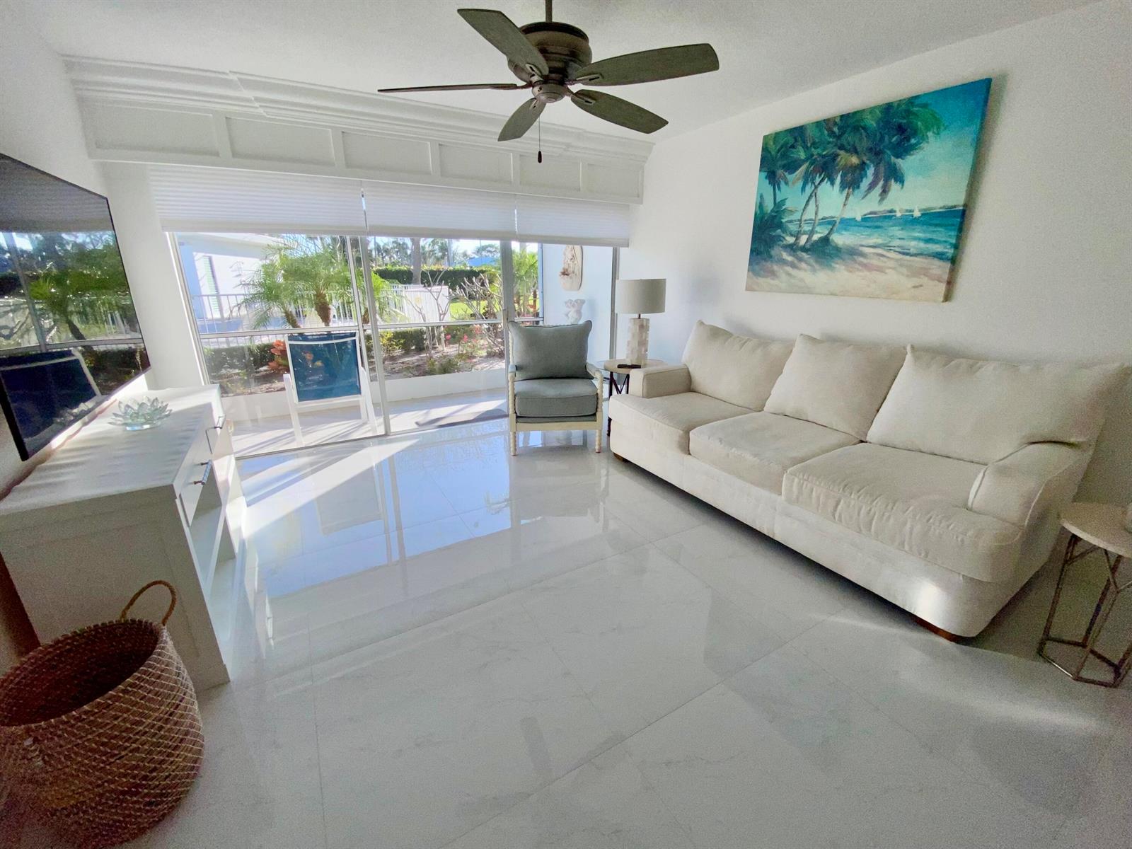 A bright living room features white tile floors, a neutral sofa, and large sliding glass doors — 331 Tequesta Drive # 118, Tequesta FL 33469, TEQUESTA, FL