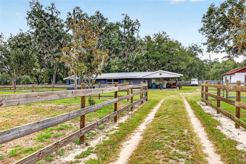 A dirt driveway leads toward a house with a metal roof and a covered carport — 5702 TINDALE ROAD, PLANT CITY, FL