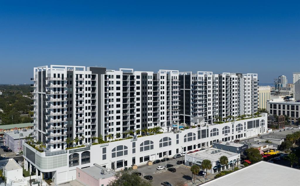 An aerial view of a large, modern white apartment building with balconies and ground-floor retail — 1000 1ST AVENUE N UNIT C1, ST PETERSBURG, FL