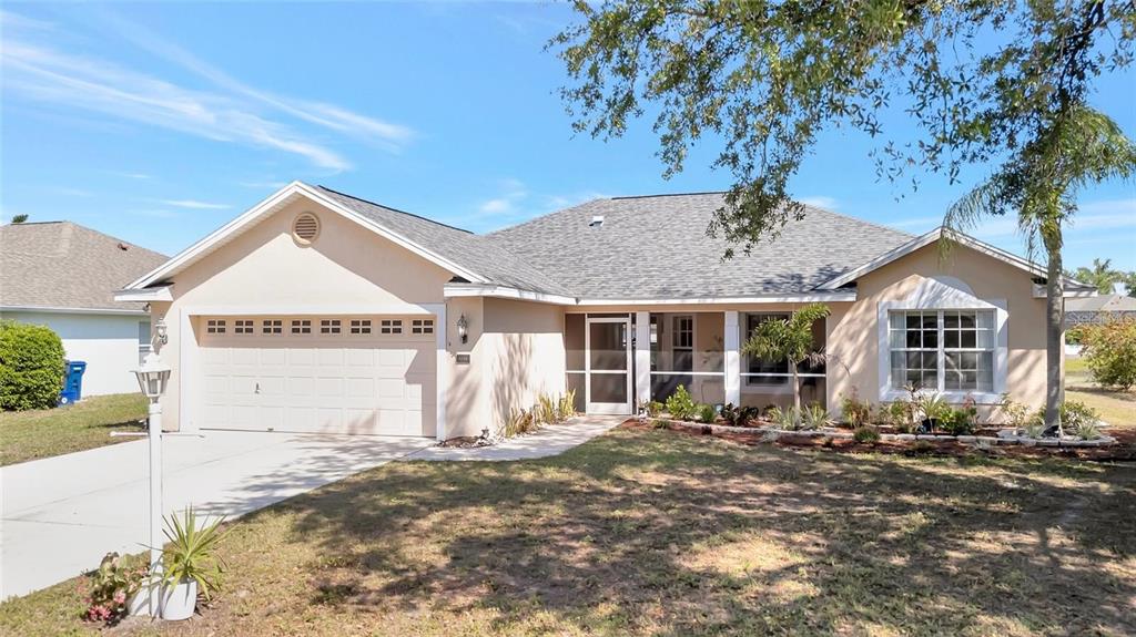 A single-story suburban house with a beige stucco exterior, a two-car garage, and a screened entryway — 4538 35TH AVENUE CIRCLE E, PALMETTO, FL