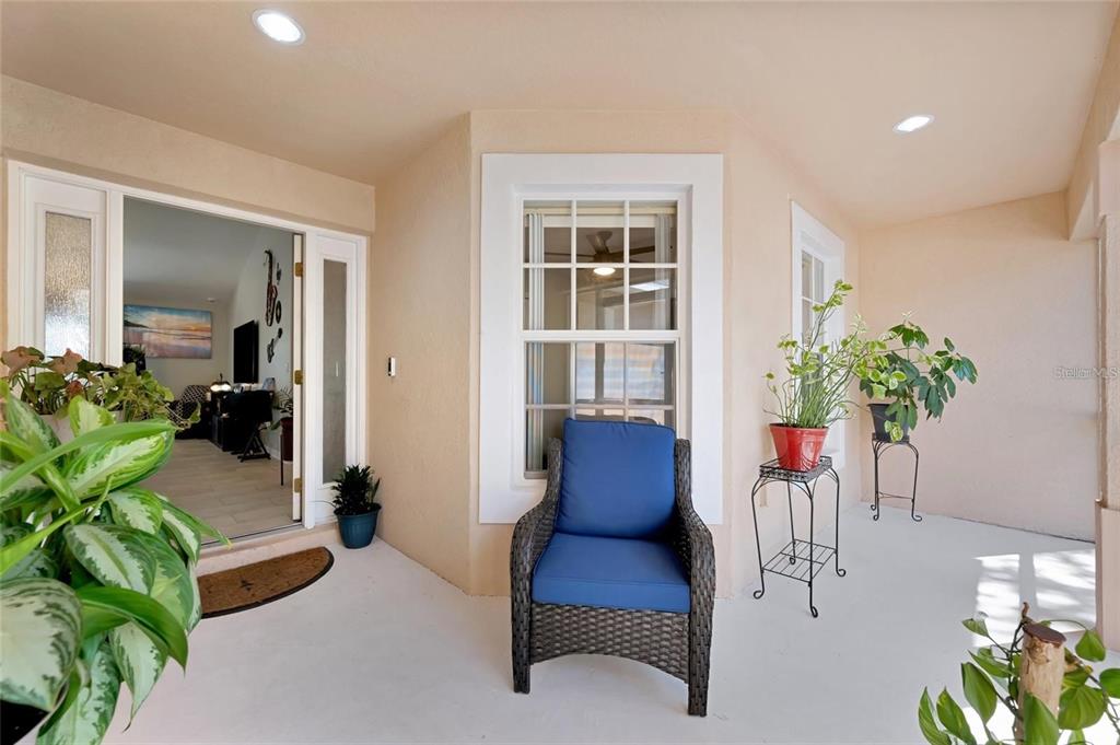 A covered porch features a wicker chair, potted plants, and an open doorway to the interior — 4538 35TH AVENUE CIRCLE E, PALMETTO, FL