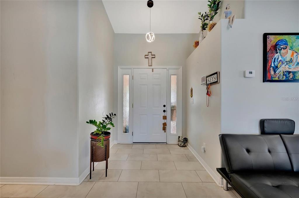 A bright entryway features a white front door, tile flooring, and a black sofa — 4538 35TH AVENUE CIRCLE E, PALMETTO, FL