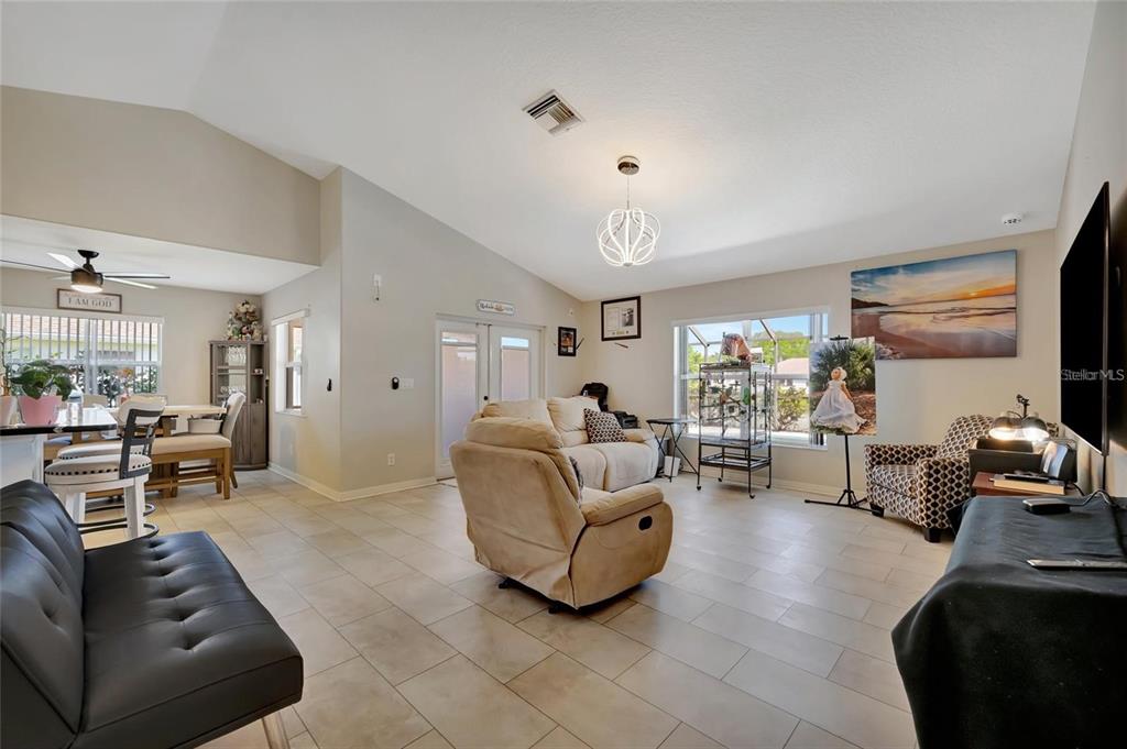 A living room with tile flooring, vaulted ceilings, a beige sofa, and a dining area — 4538 35TH AVENUE CIRCLE E, PALMETTO, FL
