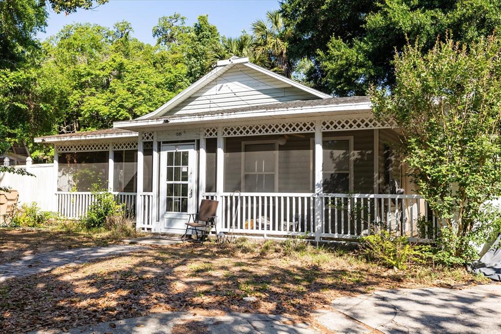 A single-story house features a white screened-in front porch with lattice trim and railings — 1505 E CROOKED LAKE DRIVE, EUSTIS, FL