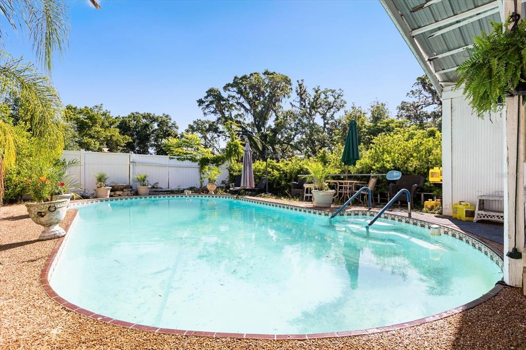 An outdoor swimming pool with a patio area, surrounded by a white fence and trees — 1505 E CROOKED LAKE DRIVE, EUSTIS, FL