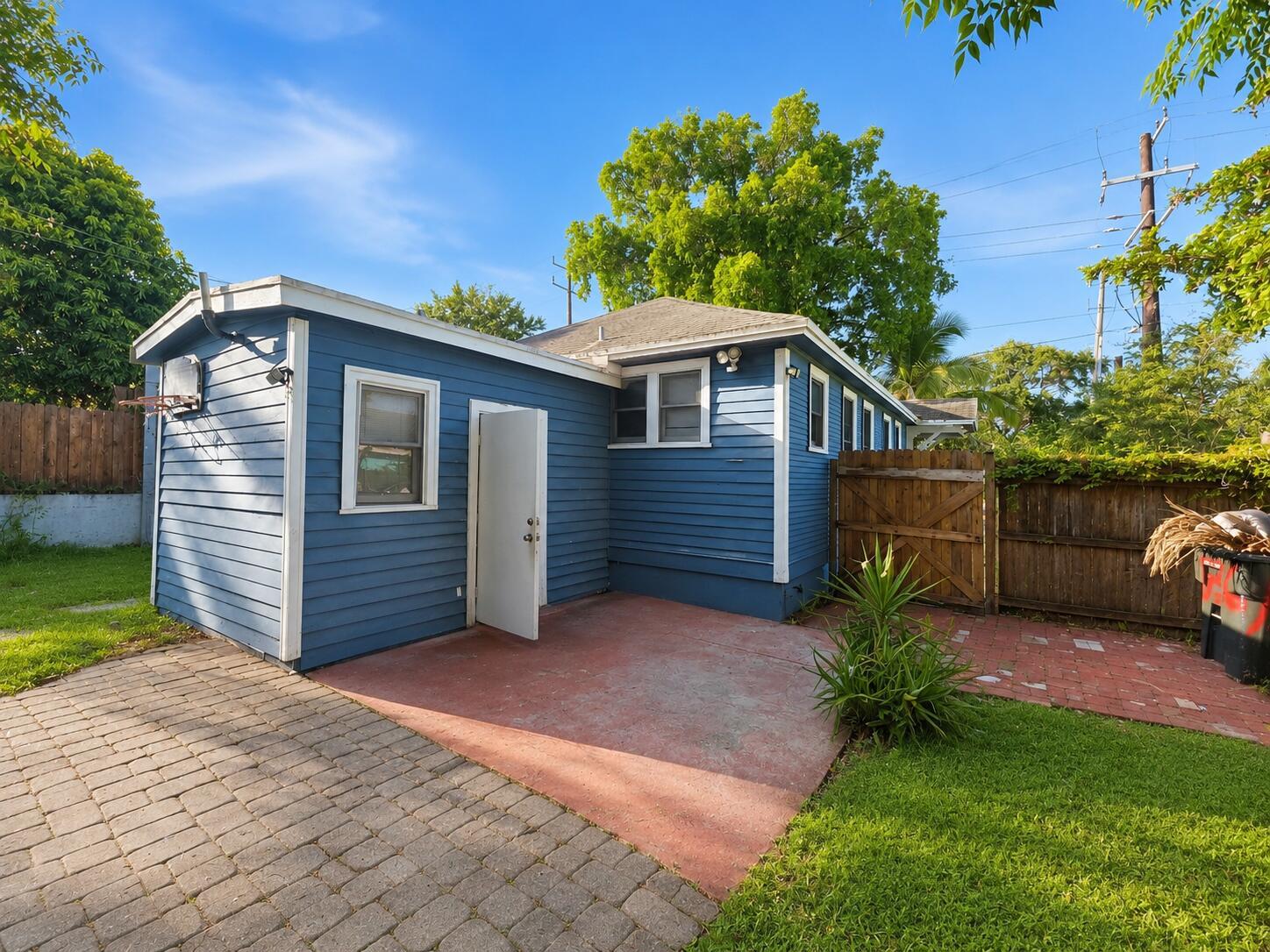 A blue-sided detached building with a concrete patio, a wooden fence, and a grassy yard — 1736 7th Avenue N, FL 33460, FL