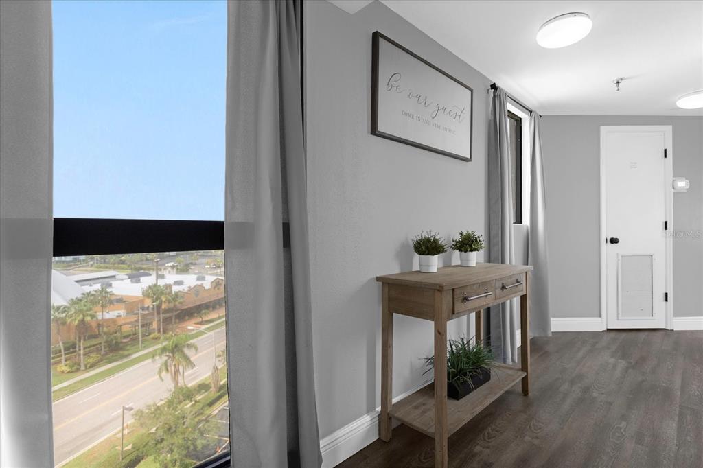 A room with a window view, a wooden console table, and a wall sign — 6165 CARRIER DRIVE UNIT 2901, ORLANDO, FL