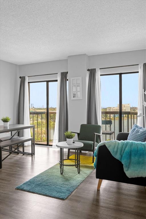 A living and dining area features wood-look flooring, sliding glass doors, and a balcony view — 6165 CARRIER DRIVE UNIT 2901, ORLANDO, FL