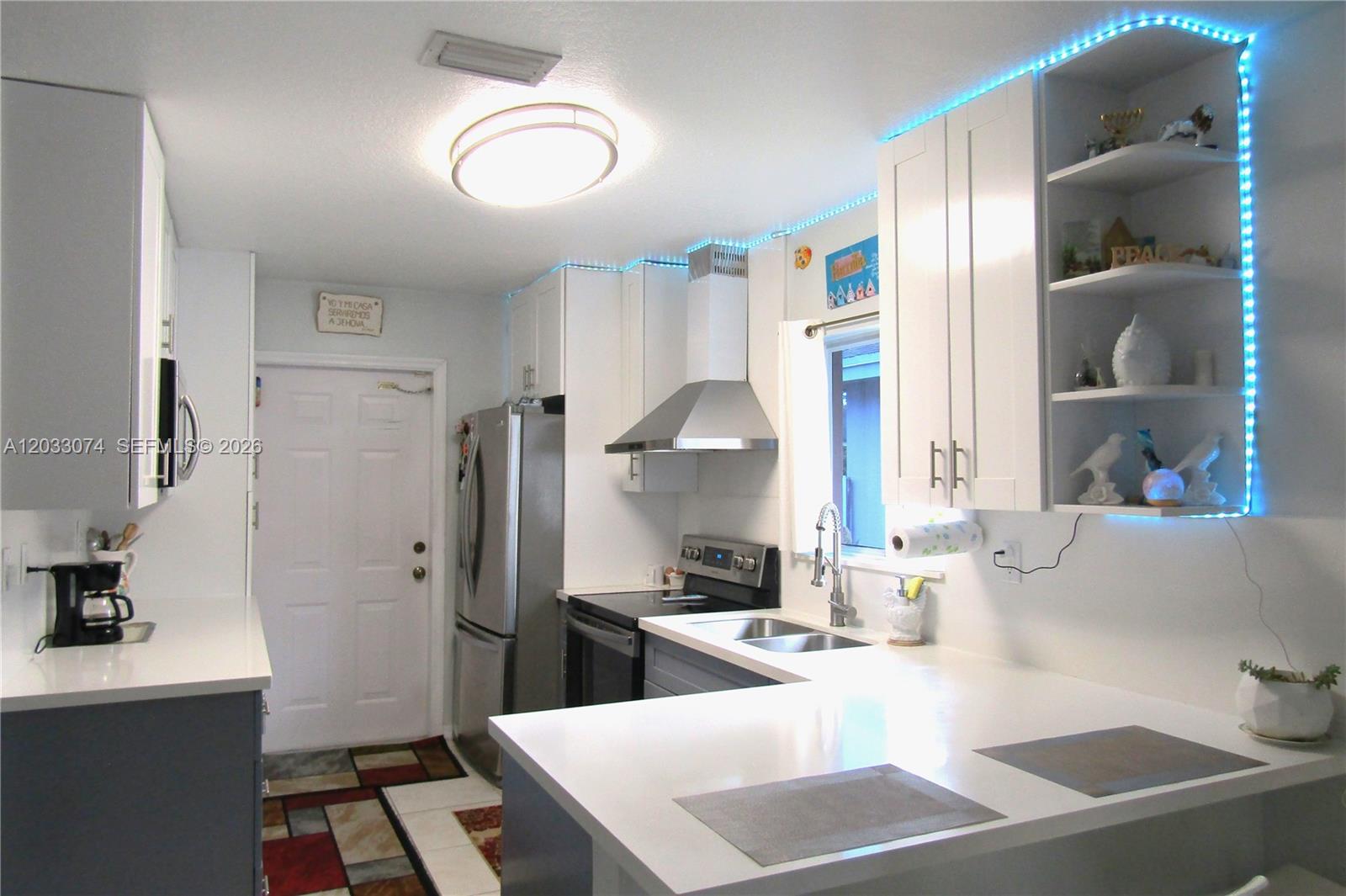 A kitchen features white cabinets, stainless steel appliances, a peninsula countertop, and blue LED lighting — 942 SW 8th Pl, Florida City FL 33034, FLORIDA CITY, FL