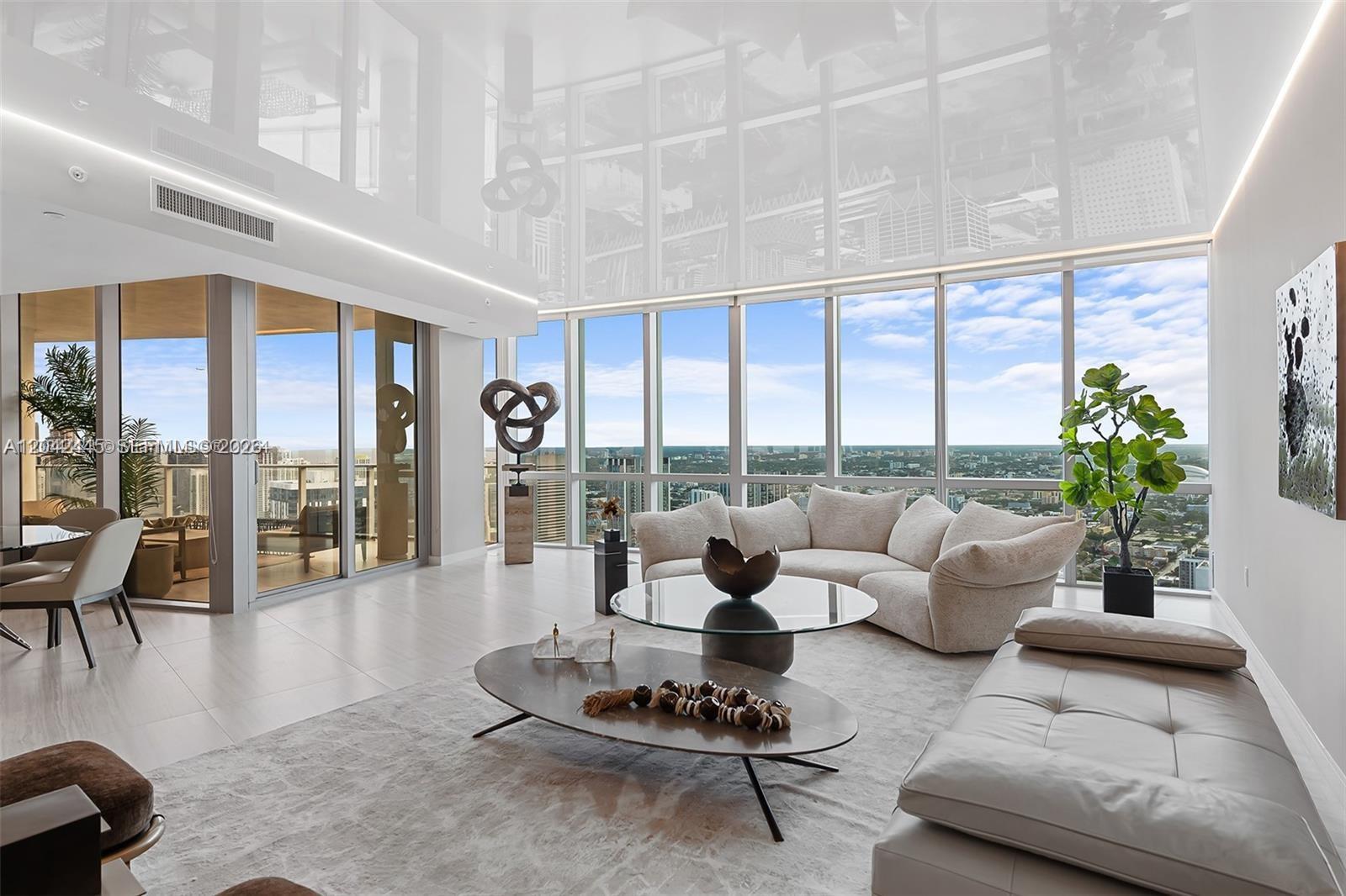A modern living room features floor-to-ceiling windows, a reflective ceiling, and panoramic city views — 851 NE 1st Ave # 4912, Miami FL 33132, MIAMI, FL