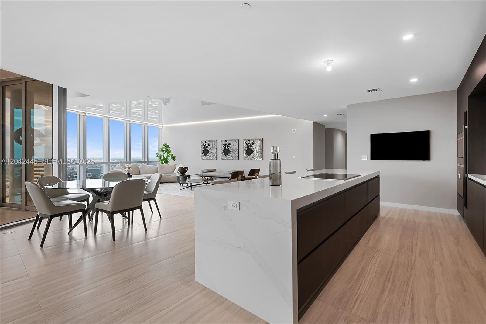 A modern open-plan kitchen and dining area features a large marble island and floor-to-ceiling windows — 851 NE 1st Ave # 4912, Miami FL 33132, MIAMI, FL