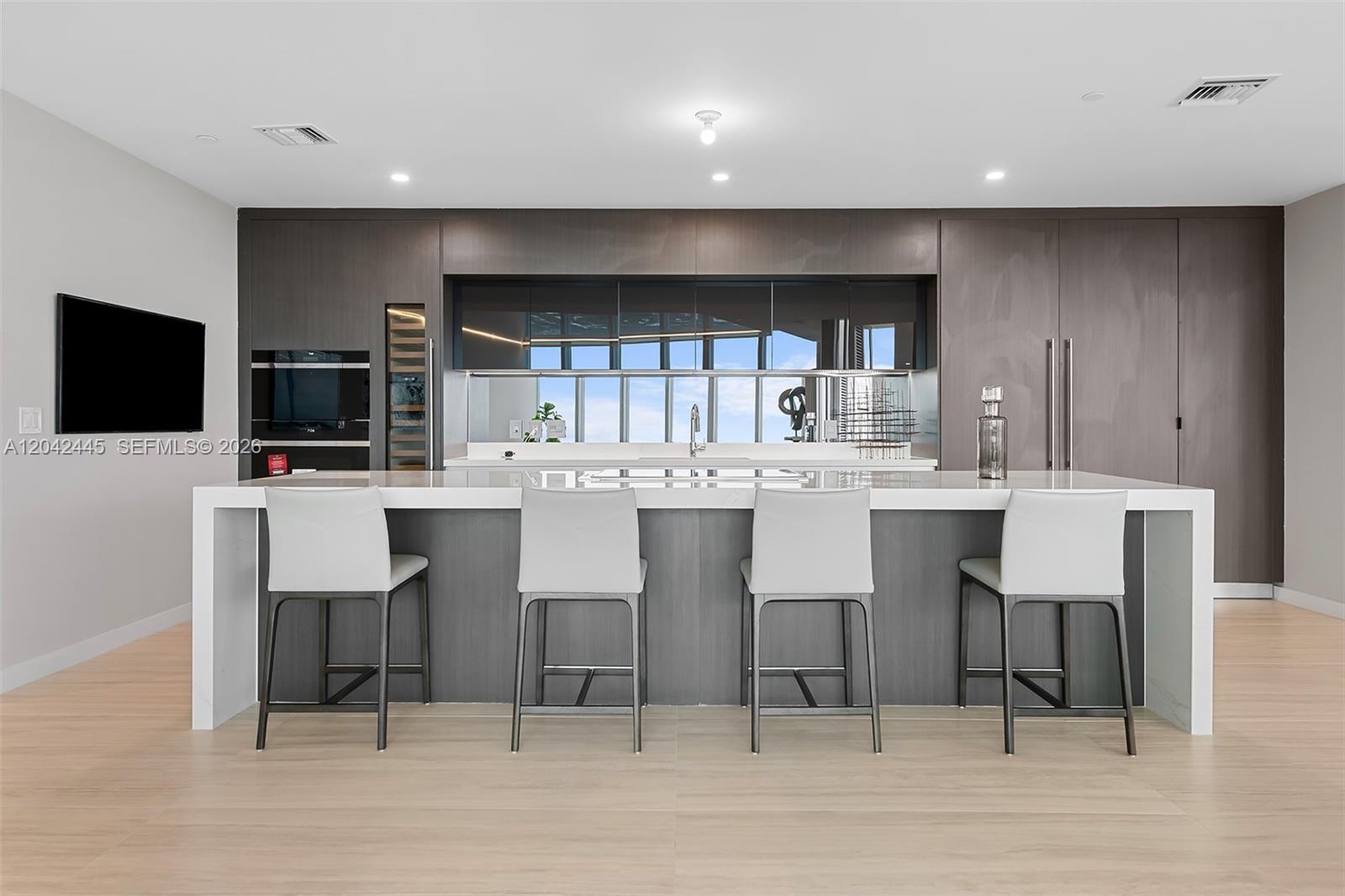A modern kitchen features a large white island, dark wood cabinetry, and four bar stools — 851 NE 1st Ave # 4912, Miami FL 33132, MIAMI, FL