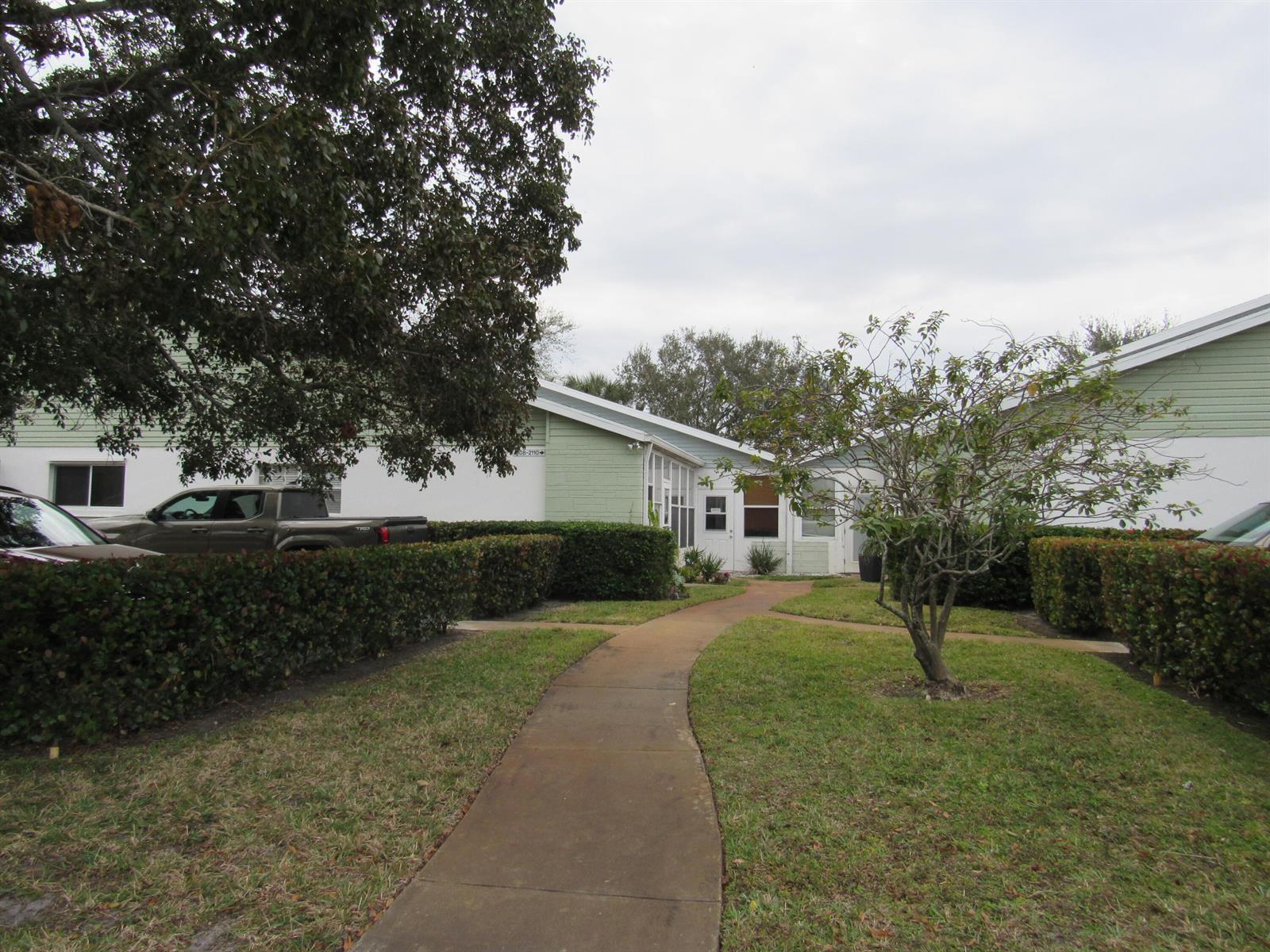 A sidewalk leads to the entrance of a single-story building with green and white siding — 2110 SE Edler Drive, Stuart FL 34994, STUART, FL