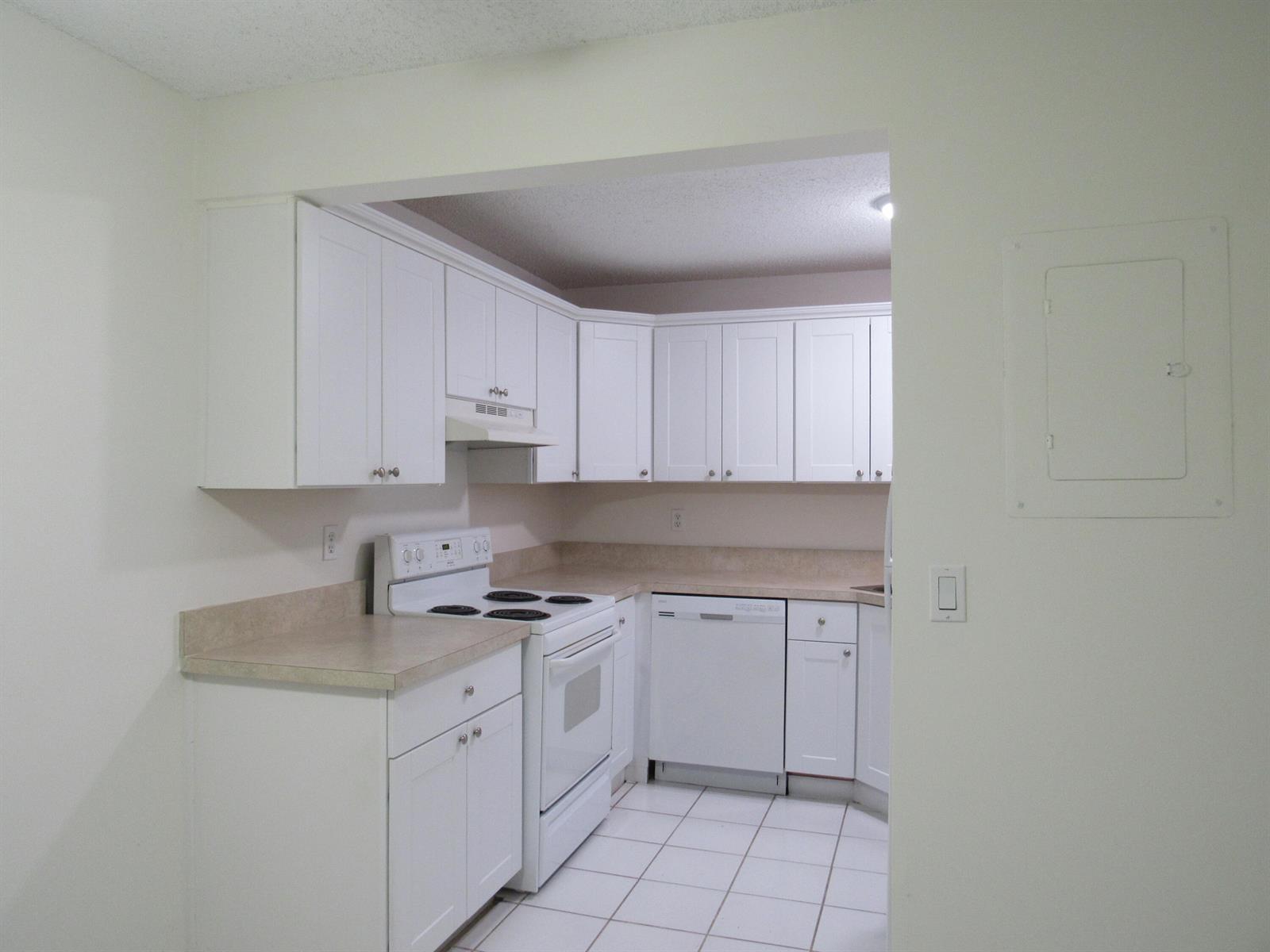 A kitchen with white cabinets, white appliances, and light-colored countertops on a tiled floor — 2110 SE Edler Drive, Stuart FL 34994, STUART, FL