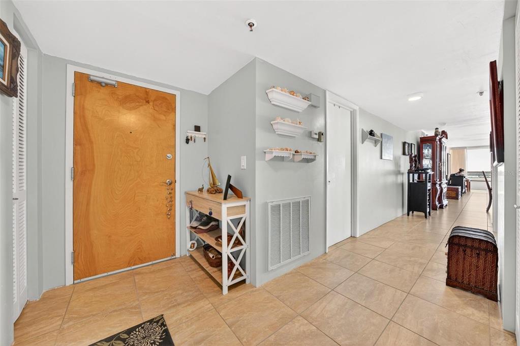 An entryway with tiled floors, a wooden door, and a small shelving unit — 3743 S ATLANTIC AVENUE UNIT 7A00, DAYTONA BEACH, FL