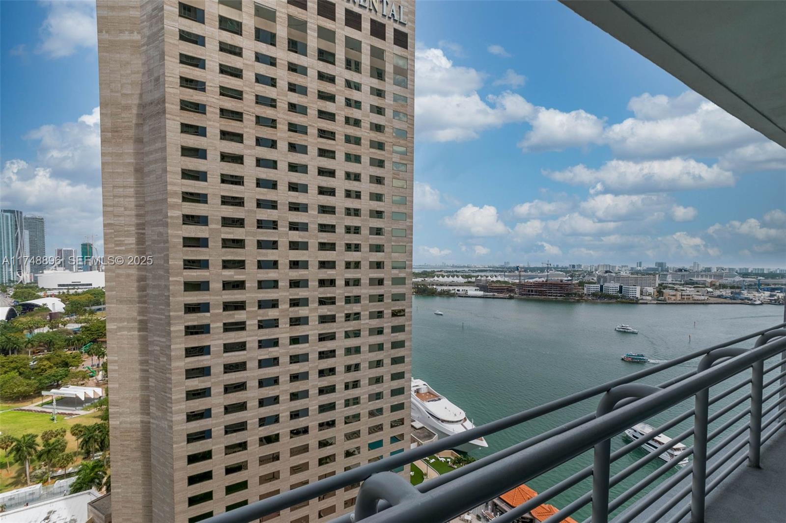 A high-rise balcony overlooks a large building, a waterway with boats, and a distant city skyline — 335 S Biscayne Blvd # 2402, Miami FL 33131, MIAMI, FL