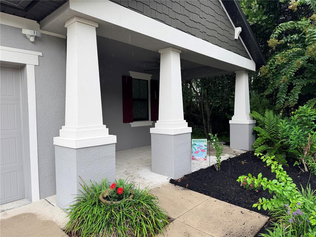 A gray house with a covered front porch, white columns, and dark shingle siding — 8429 AUBURN RISE COURT, LAND O LAKES, FL