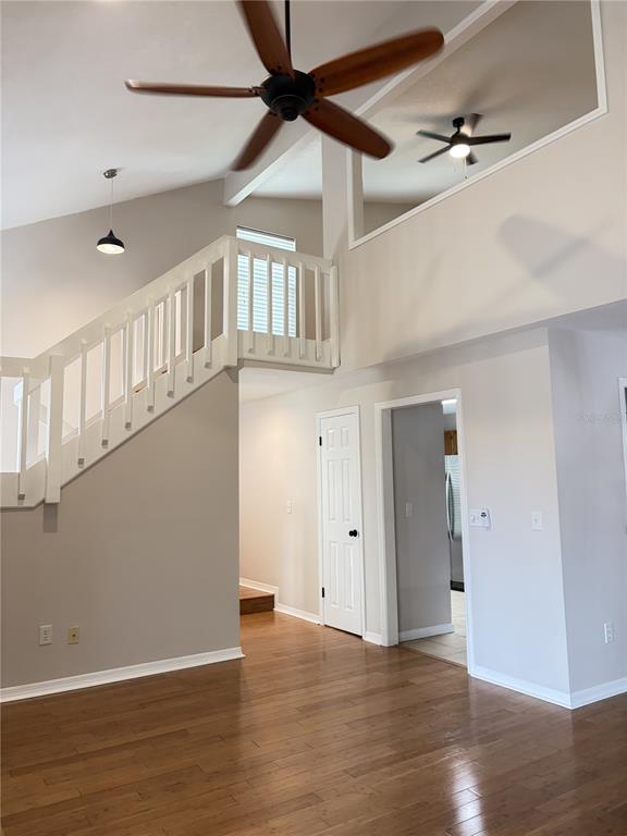 A living area features hardwood floors, a staircase with white railings, and a vaulted ceiling — 3156 VALLEY OAKS DRIVE UNIT 614, TAMPA, FL