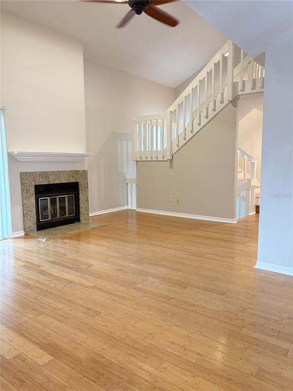 A living room features a fireplace, light wood flooring, and a staircase with white railings — 3156 VALLEY OAKS DRIVE UNIT 614, TAMPA, FL