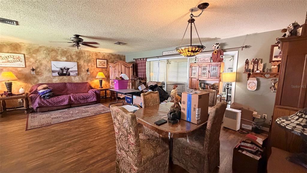 A living and dining area with wood-look flooring, a purple sofa, and a dining set — 8822 E CRESCO LANE, INVERNESS, FL