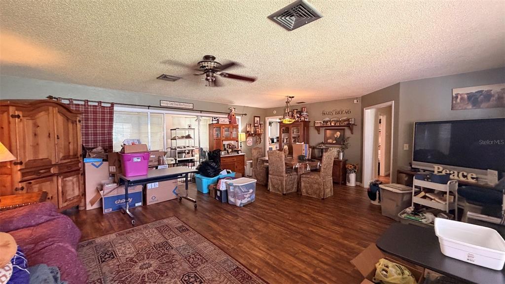 A living and dining area features wood-look flooring, a ceiling fan, and various storage containers — 8822 E CRESCO LANE, INVERNESS, FL