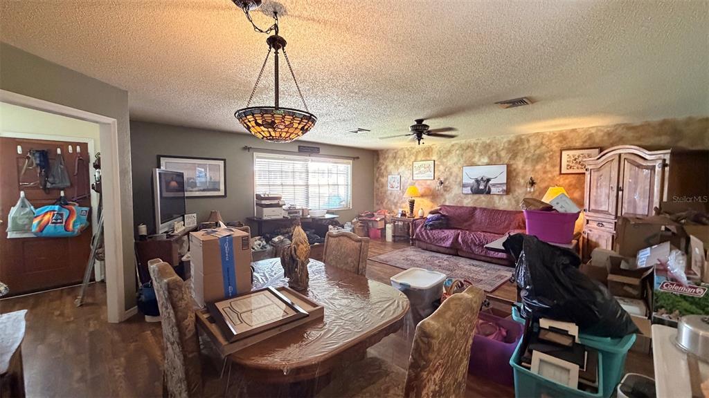 A dining area with a stained-glass pendant light opens into a living room with carpet — 8822 E CRESCO LANE, INVERNESS, FL