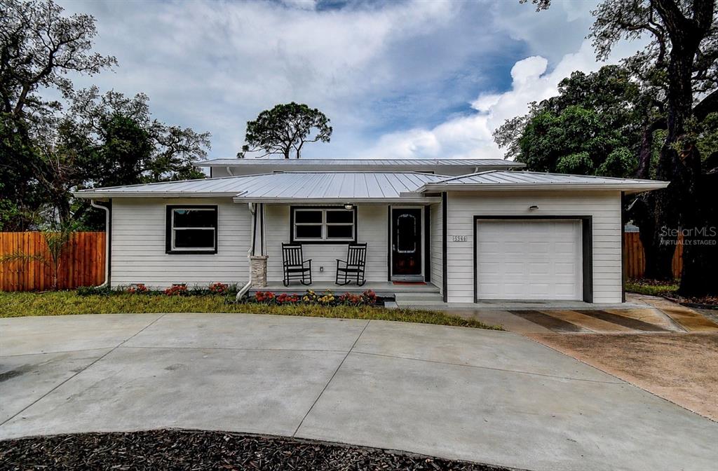 A single-story house with white siding, a metal roof, and a front-facing garage — 5546 113TH STREET, SEMINOLE, FL