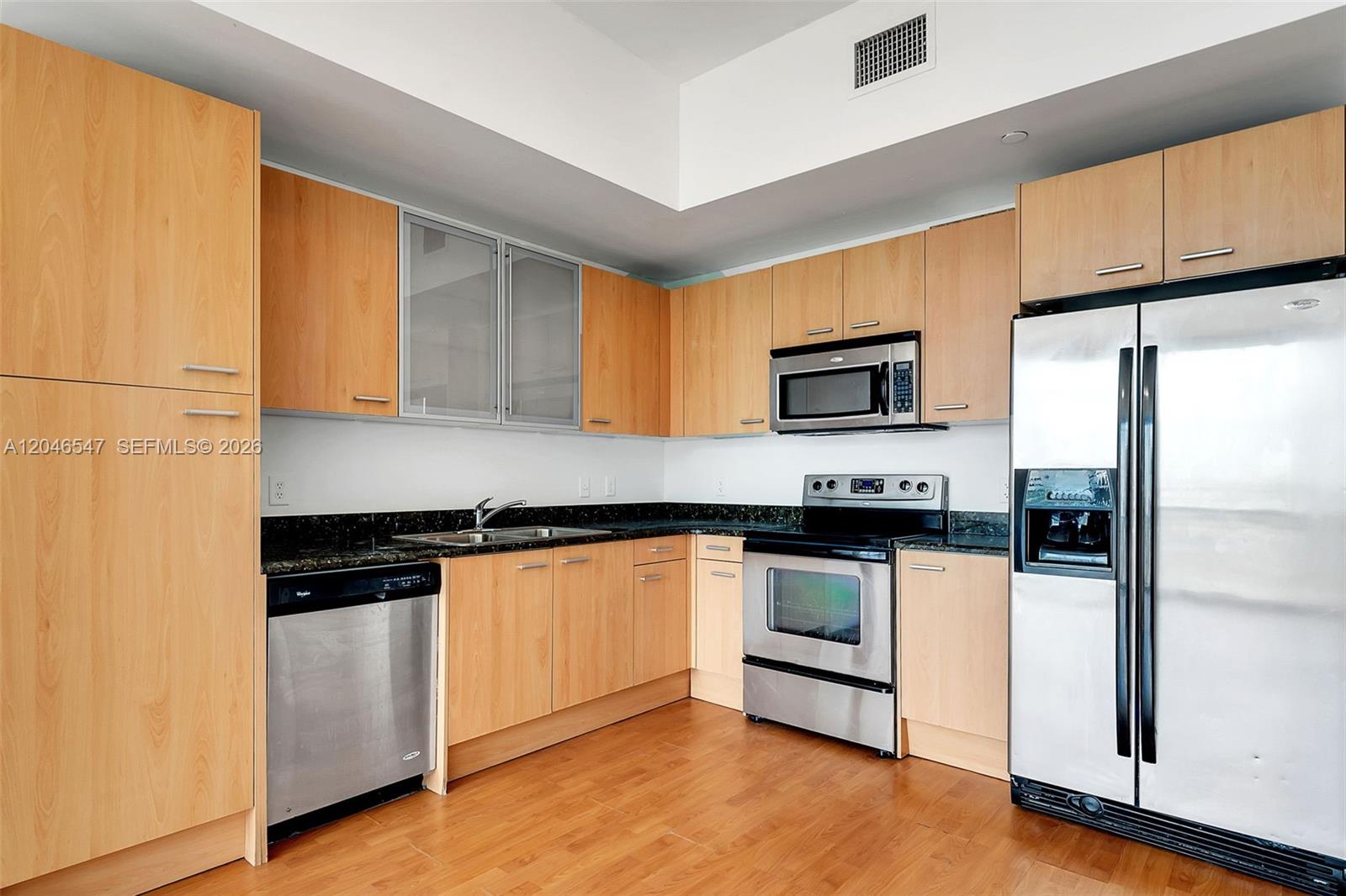 A kitchen features light wood cabinets, stainless steel appliances, and dark granite countertops — 1350 NW 8th Ct # 5, Miami FL 33136, MIAMI, FL