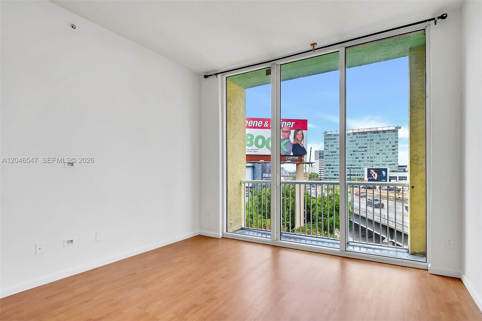 An empty room with wood-look flooring, white walls, and a large balcony with city views — 1350 NW 8th Ct # 5, Miami FL 33136, MIAMI, FL