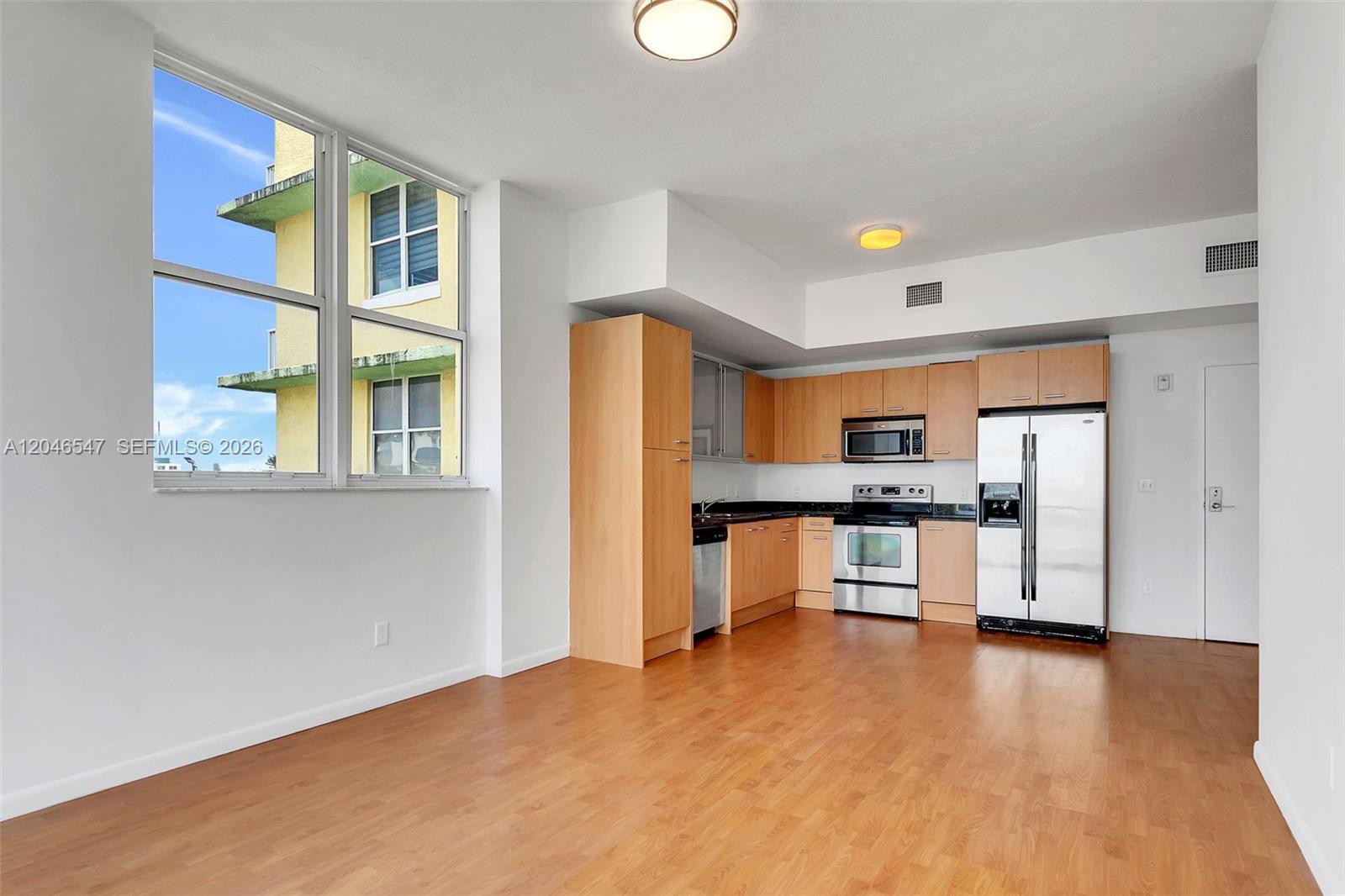 A kitchen with light wood cabinets and stainless steel appliances sits beside a large window — 1350 NW 8th Ct # 5, Miami FL 33136, MIAMI, FL