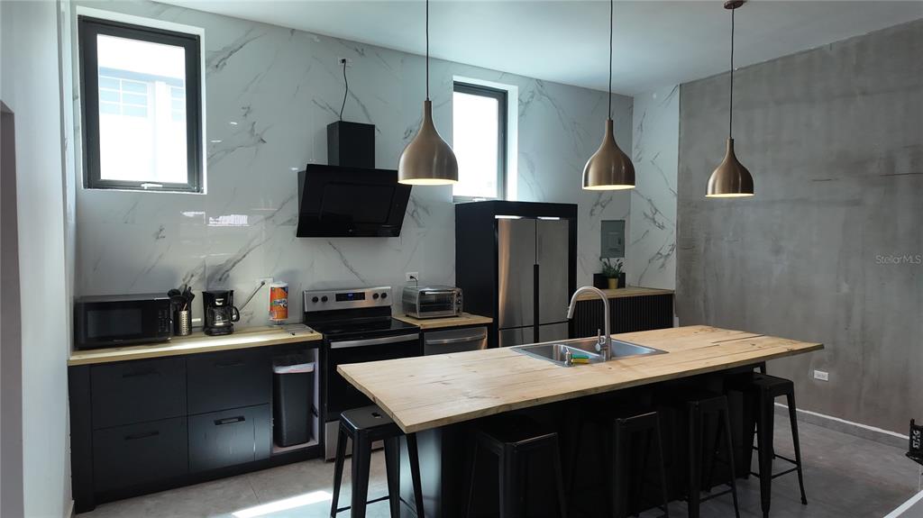 A modern kitchen with a large island and ping pong table in an open room — 73 CALLE TAPIA UNIT 5, SAN JUAN, PR