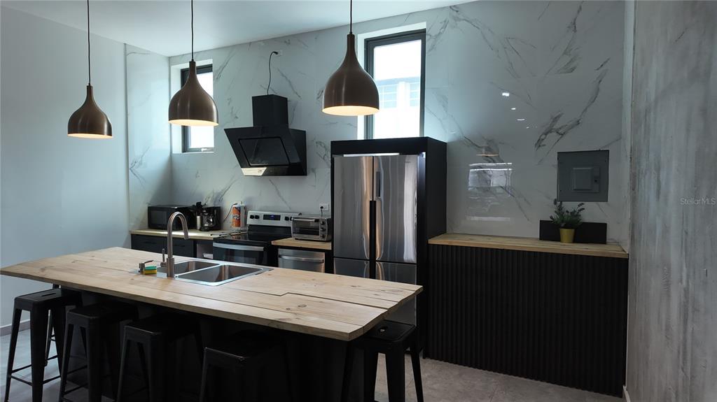 A modern kitchen features black cabinetry, a wood-topped island, and white marble-patterned wall panels — 73 CALLE TAPIA UNIT 5, SAN JUAN, PR