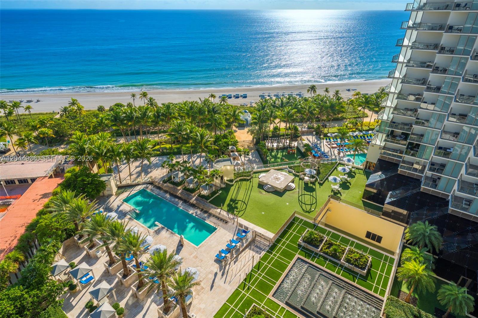 An aerial view shows a high-rise building with a pool, green space, and beach access — 9705 Collins Ave # 1402N, Bal Harbour FL 33154, BAL HARBOUR, FL