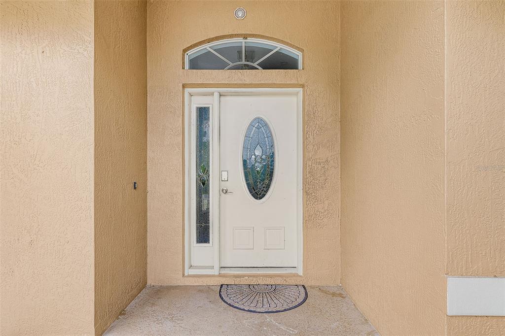 A white front door with a glass oval insert and a side light sits under an arch — 2590 ABBOTSFORD STREET, NORTH PORT, FL