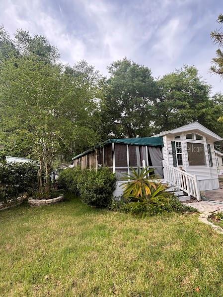 A white mobile home with a screened-in porch sits on a grassy lot with trees — 25155 NE 142ND LANE UNIT 212, FORT MC COY, FL