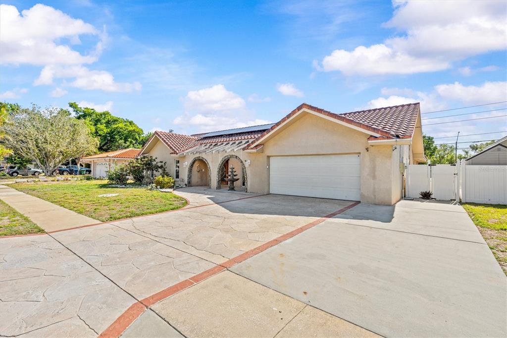 A single-story house with a tiled roof, arched entryway, and a paved driveway — 3149 CARLOS DRIVE, DUNEDIN, FL