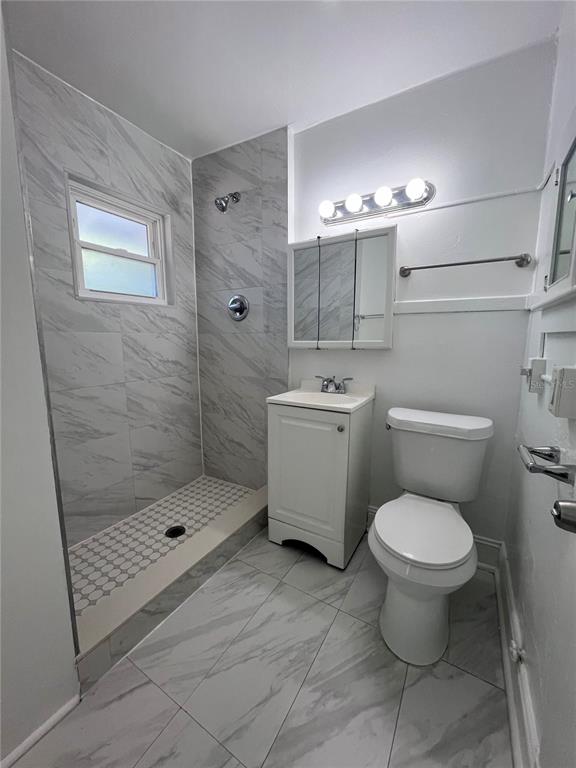 A bathroom features a walk-in shower with marble-look tile, a vanity, and a toilet — 510 E JACKSON ST UNIT 7, ORLANDO, FL