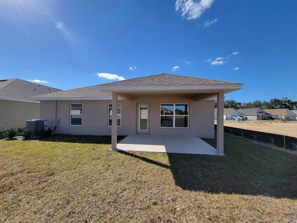 The rear exterior of a single-story house features a covered patio and a grassy yard — 4457 SW 91ST LANE ROAD, OCALA, FL